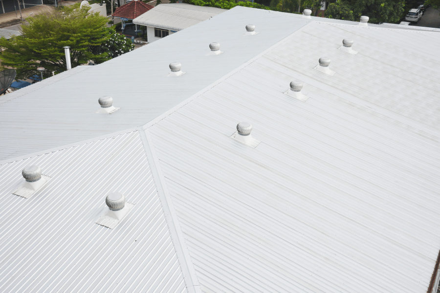 Flat white commercial roof with multiple vent stacks