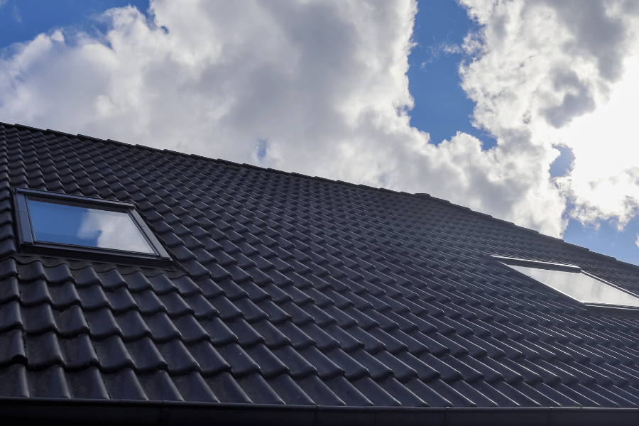 New black tile roof with skylights under a blue sky